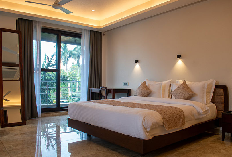 Spacious guest room with balcony overlooking lush greenery at Lakeside Manor